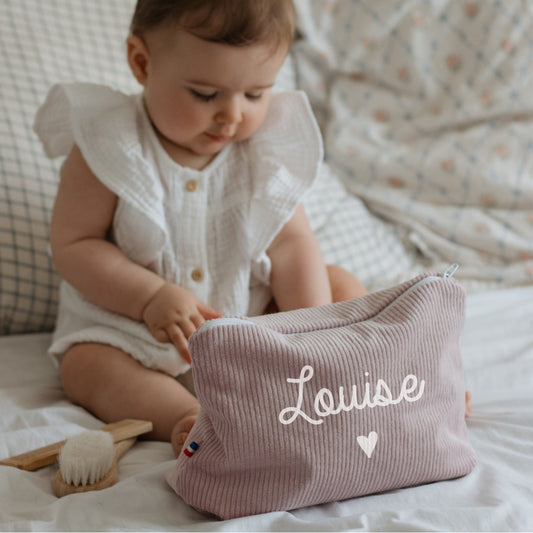 Bébé avec une trousse de toilette personnalisée au prénom en velours côtelé lila, idée cadeau de naissance fille.