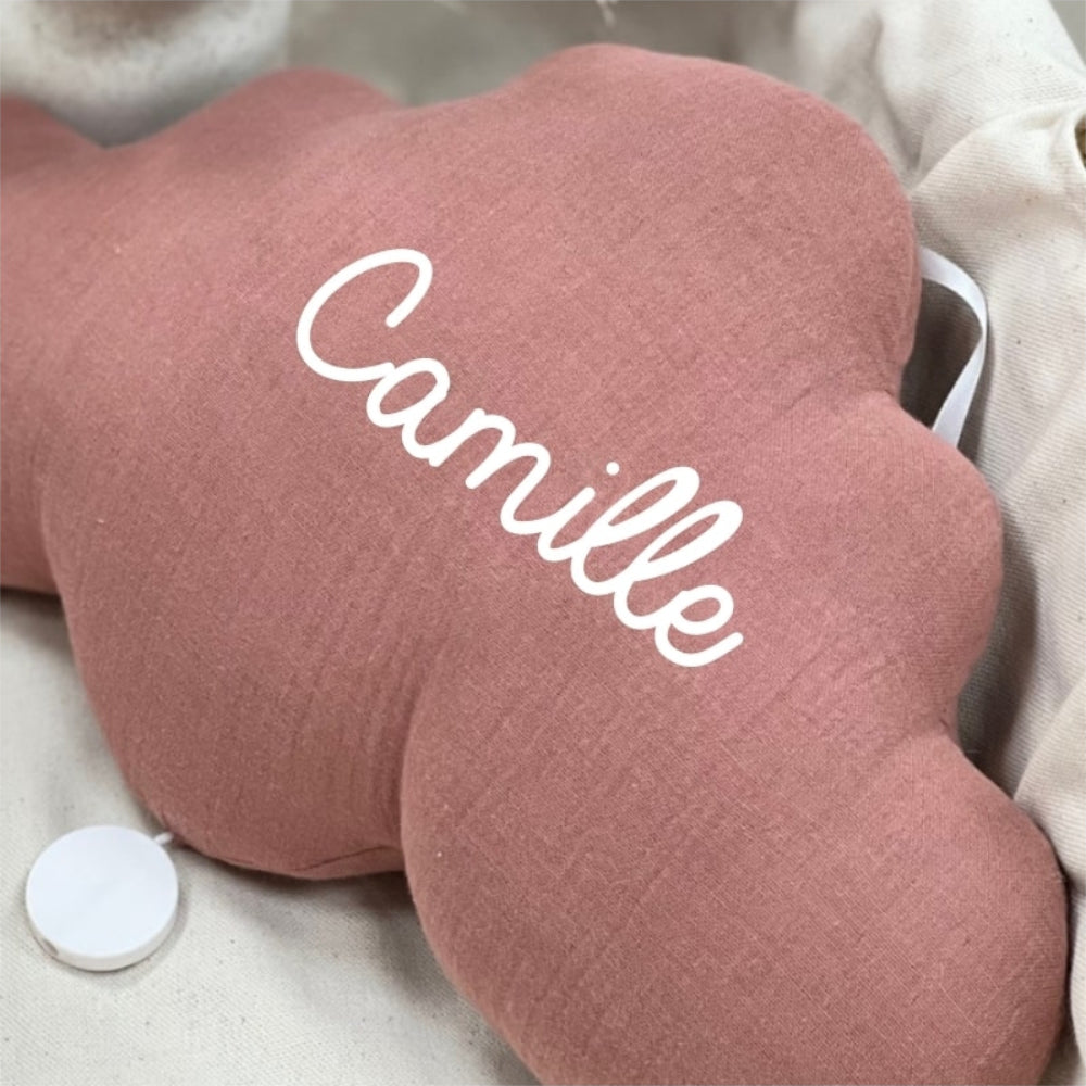 Gros plan sur la veilleuse nuage vieux rose en gaze de coton, personnalisée avec le prénom Camille en écriture cursive blanche.