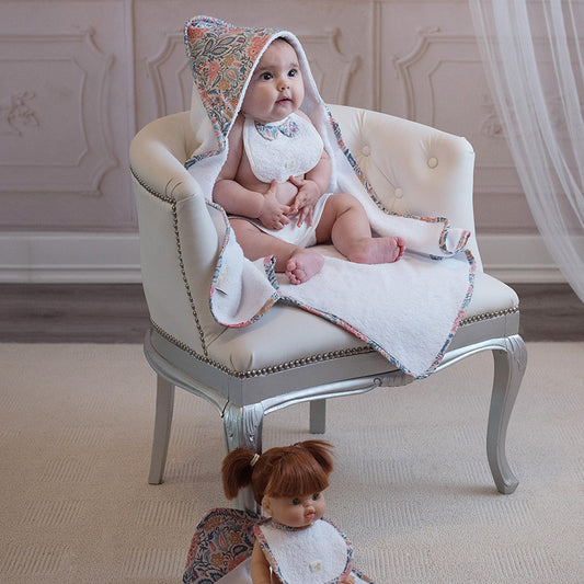 Bébé avec une cape de bain à capuche à motif, installé sur un fauteuil. La Cigogne de Lily, fabrication française spécialisée dans le linge de bain pour bébé.