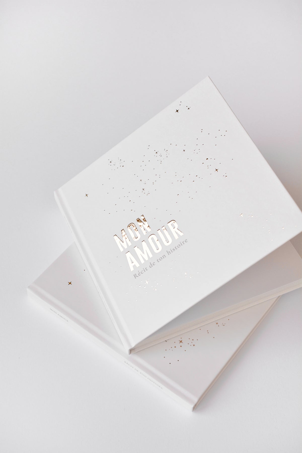 Livre de naissance Zakuw blanc et doré entre-ouvert. Design chic et épuré. Marquage doré "mon amour" brillant avec jolis reflets.