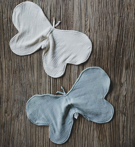 Proteges épaule anti bavouille en coton bio de la marque Baby Shower : vert sauge et écru posé sur une table en bois.